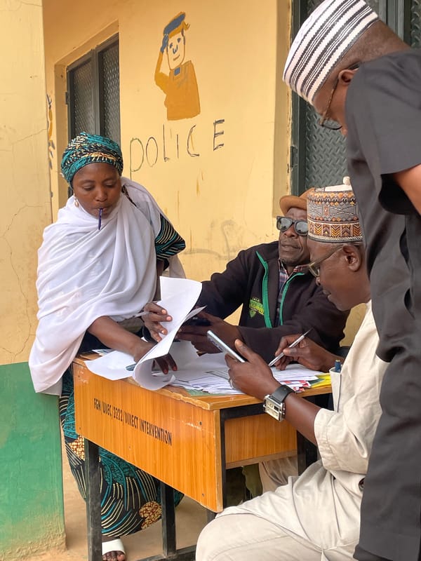 Groups gather around tables examining documents in Jos, Nigeria