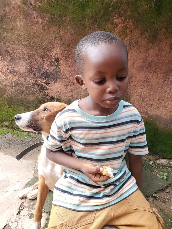 Kid shares a snack moment with a dog in Jos