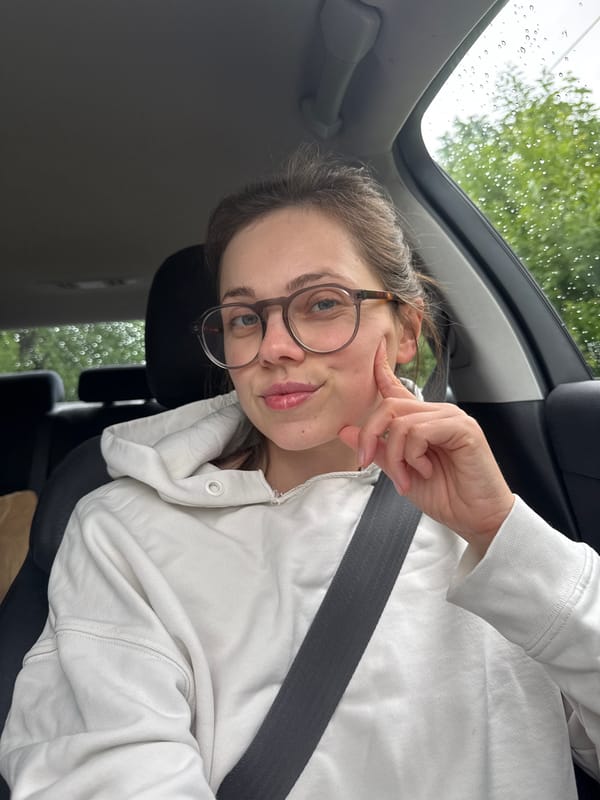 Woman in white hoodie sits in car in Vrchlabí