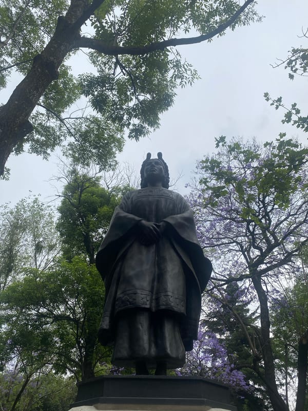 Bronze statue surrounded by blooming trees observed in Mexico City