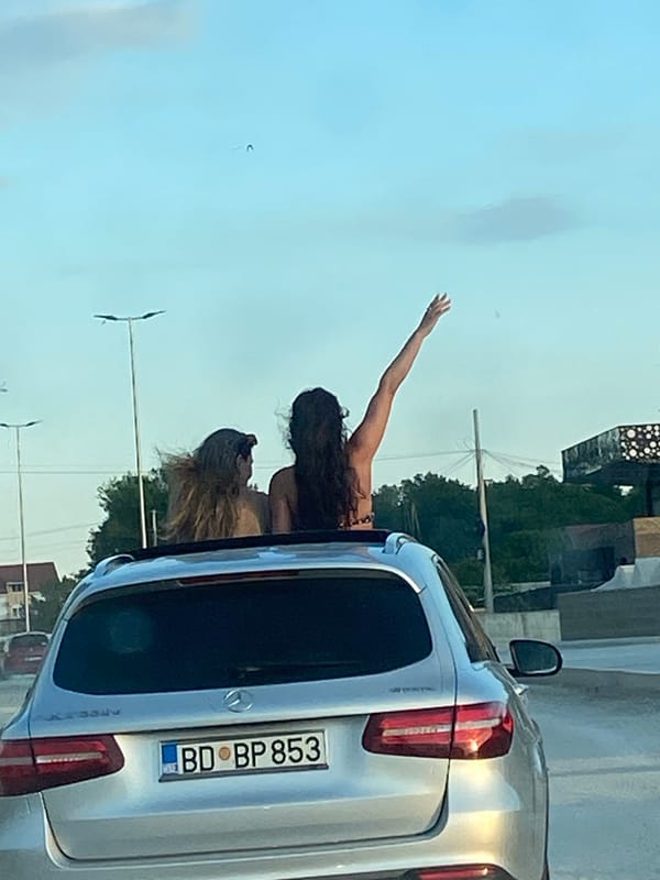 Women celebrate through sunroof on dusty Montenegro road