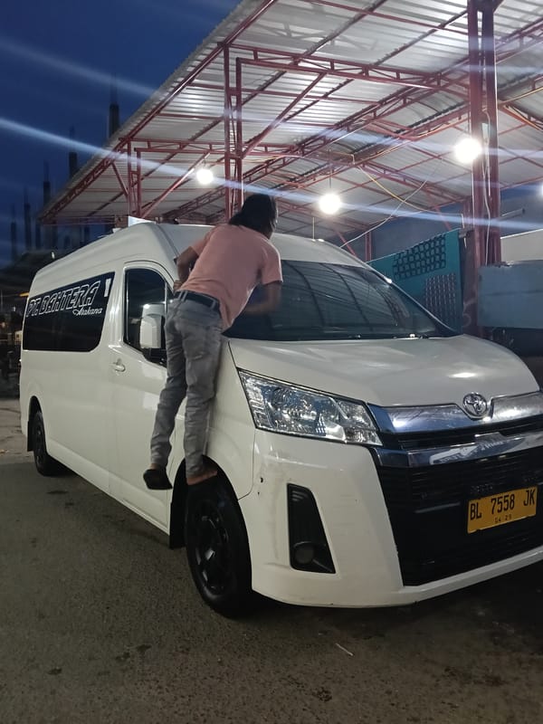 Man washes commercial van at night car wash in Indonesia