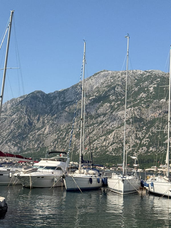 Sailboats dock at peaceful Prčanj marina beneath Montenegro mountains