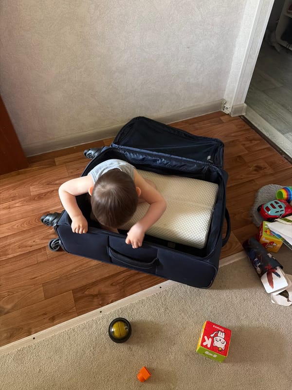 Child sits in suitcase with pillow in Ufa