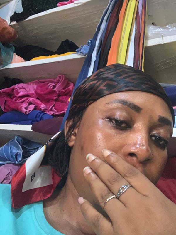 Woman seeks relief in Nigerian textile shop, children observed nearby