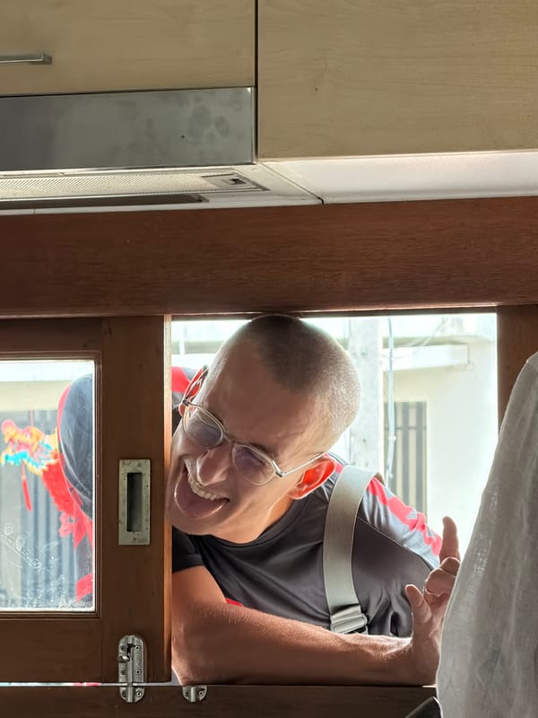 Man playfully peers through window in Chang Phueak, Thailand