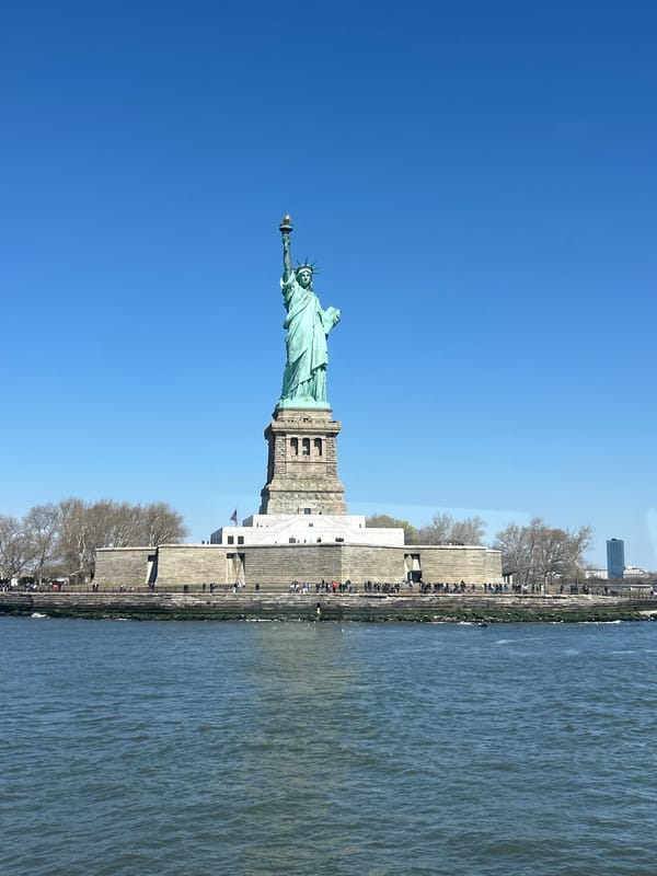 Tourist takes selfie at Statue of Liberty on sunny afternoon