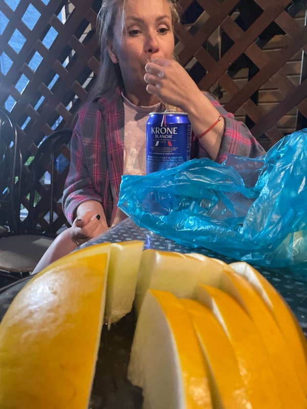 Woman dines outdoors with beer on patio evening