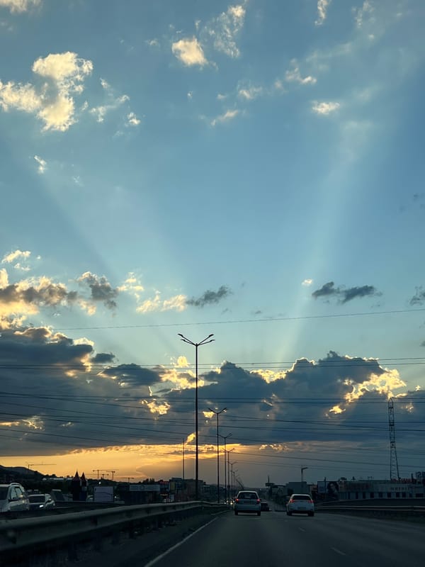 Sunbeams break through clouds over a Sofia highway at sunset.