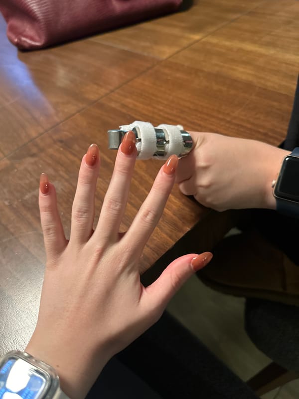 Hands, a finger splint, and a candle on a wooden table