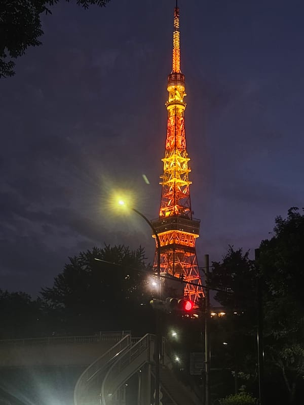 Tokyo Tower glows orange-yellow against twilight skies in Minato
