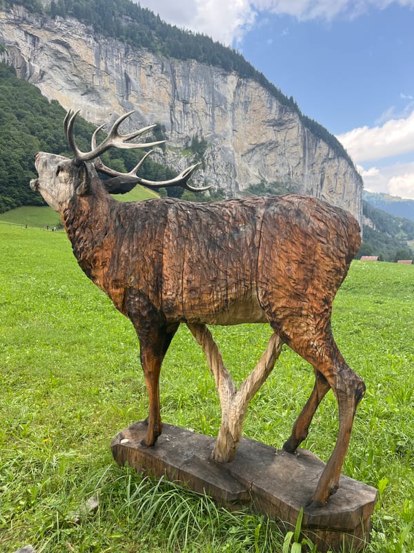 Wooden wildlife sculptures and alpine scenery in Lauterbrunnen Valley