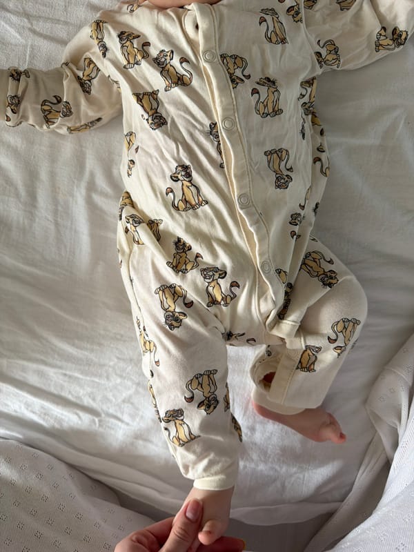 Baby in Lion King pajamas photographed with toy giraffe