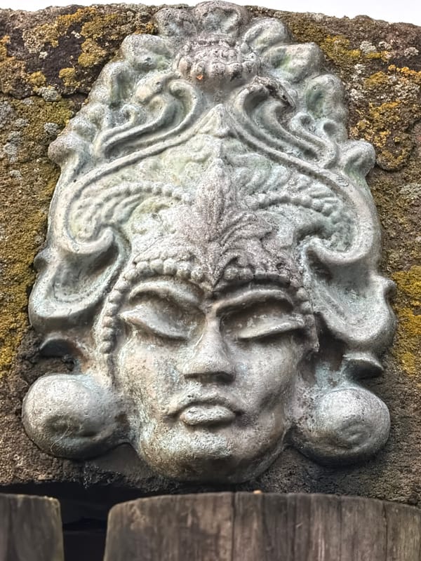 Weathered stone face carving on mossy surface in Viimsi