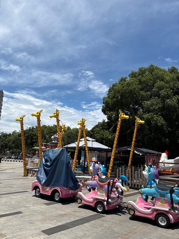 Minhang street scene: amusement rides, vendors, and a cartoon-wrapped Tesla