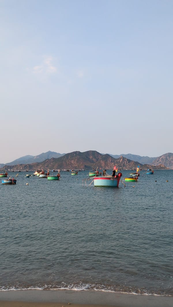 Traditional fishing boats dot Vietnam coastline near mountains