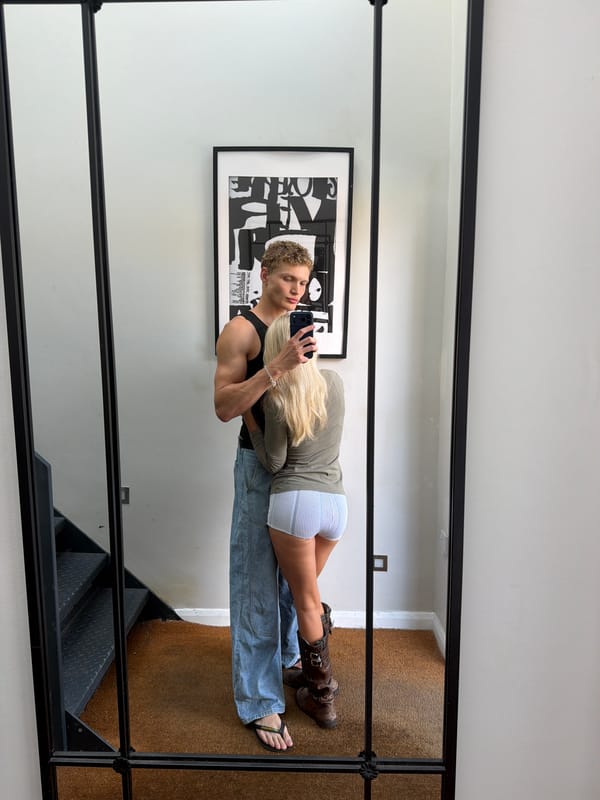 Mirror selfie in a London residential hallway, casual pose.