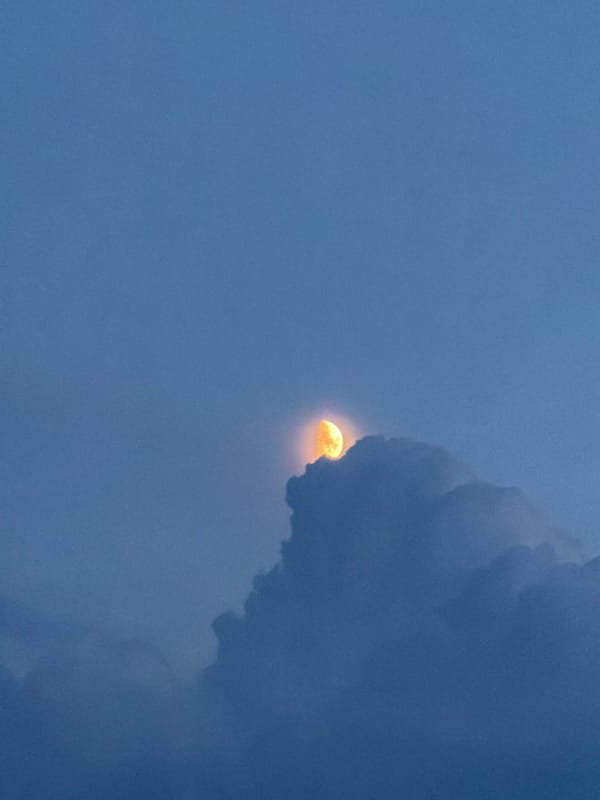 Orange moon rises through clouds over rural Shumki