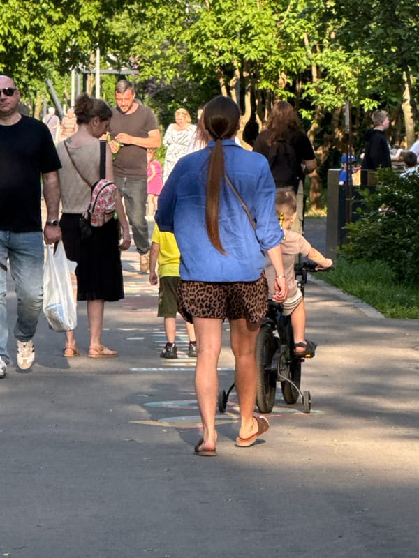 Mixed-age group strolls through Moscow park in summer attire