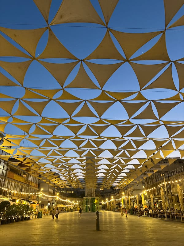 Yellow fabric canopy shades Tel Aviv street at dusk