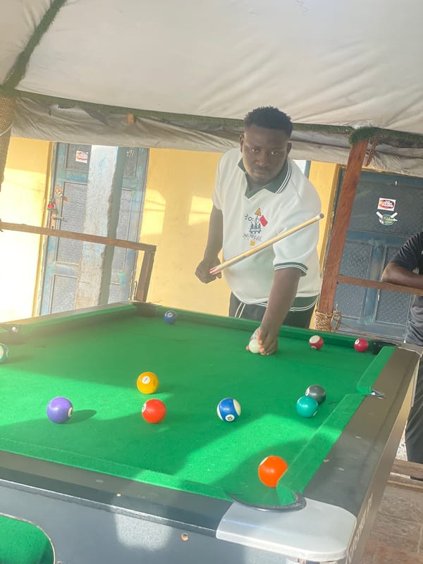 Young men play pool at outdoor venue in Lokoja