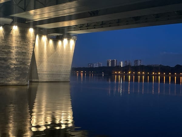 Under a bridge at dusk, Khimki Reservoir glows in warm light