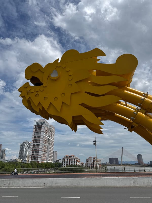 Yellow dragon sculpture on a bridge, cloudy city skyline beyond