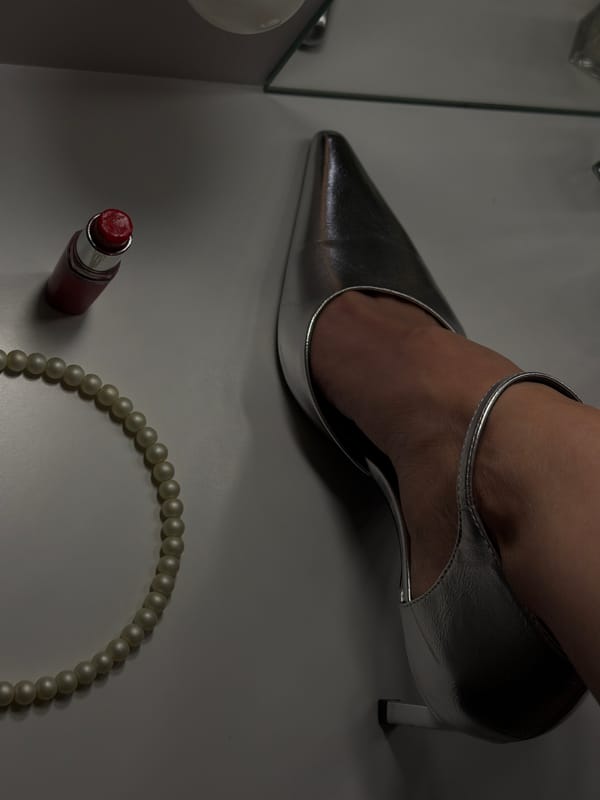 Silver heel, lipstick, pearls arranged on white surface in Bulgaria