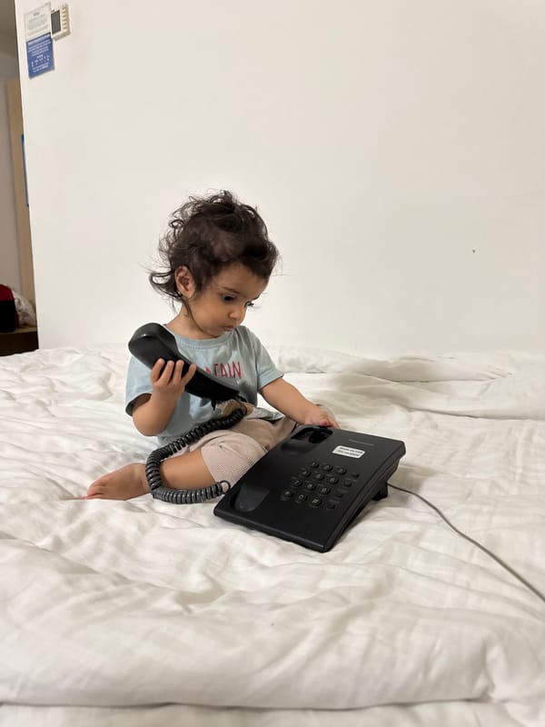 Child plays with telephone on bed in Indian home
