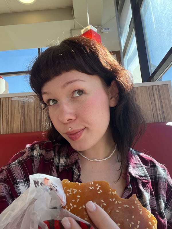 Young person enjoys burger at Izhevsk cafe during sunny afternoon