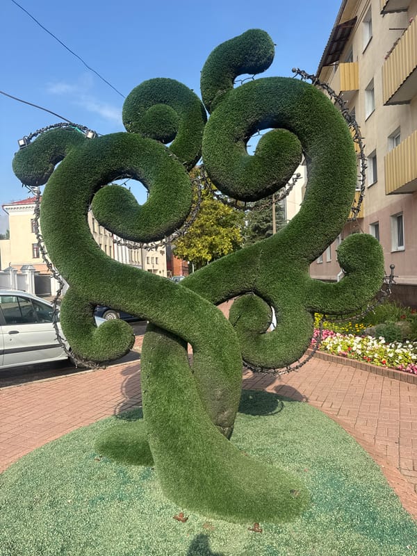 Decorative sculptures, bold cars, and a glass pyramid in one urban spot