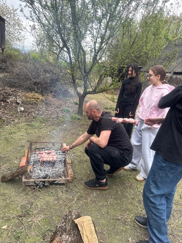 People gather in rural yard amid old buildings in Georgia