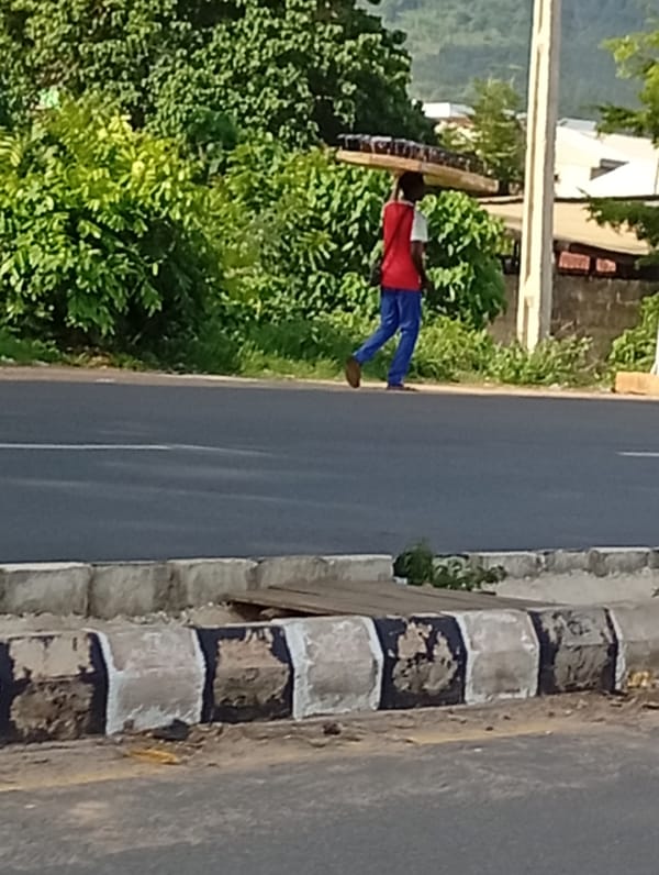 Street vendors carry goods through Adankolo, Nigeria