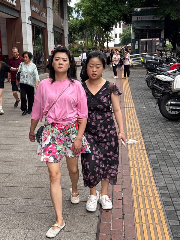 Women gather on sidewalk, check phone in Yuzhong District