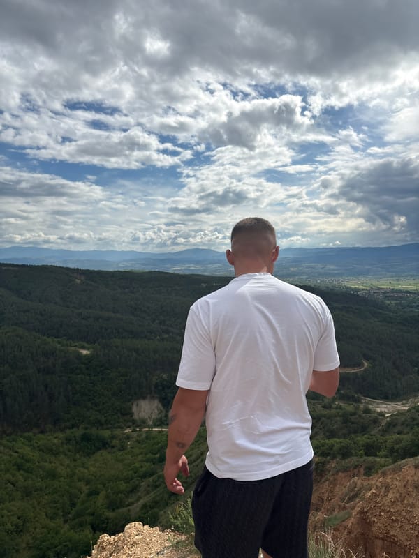 Man stands at cliff edge overlooking valley in Porominovo