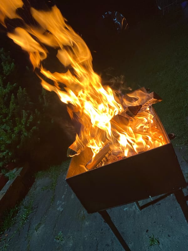 Fire pit burns as woman enjoys waffle cookie in Красный Маяк