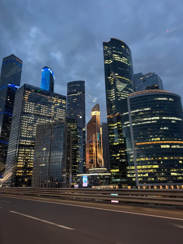 City skyscrapers glow against a dark cloudy night sky.