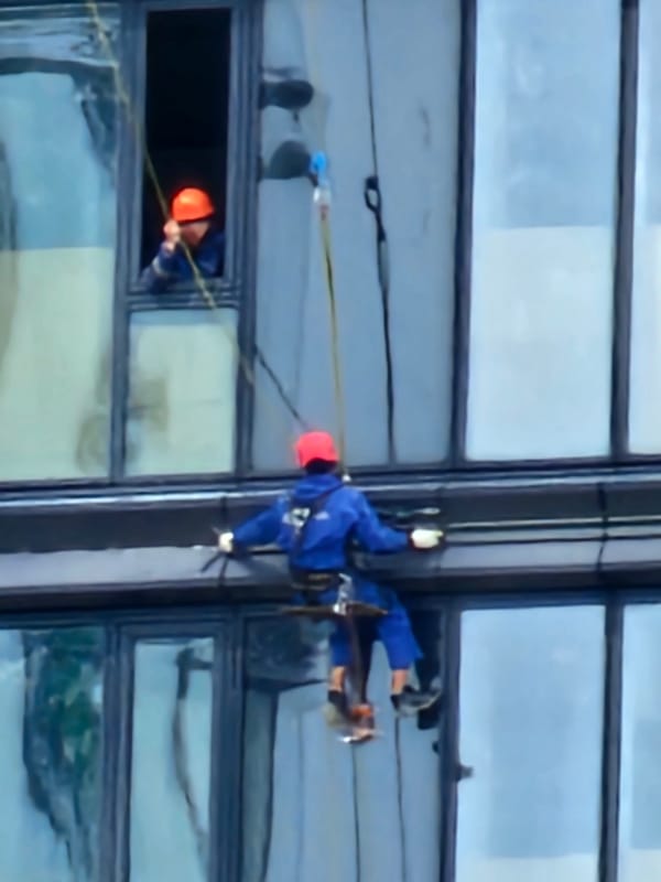 Window cleaners rappel down a Moscow glass-facade building