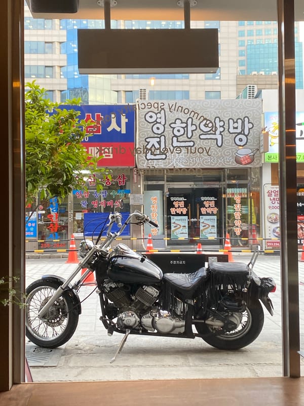 Black motorcycle parked on Daegu sidewalk during morning hours