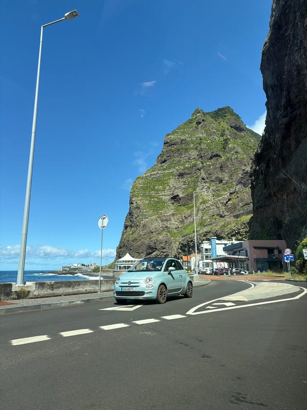 Blue Fiat turns on coastal road near São Vicente mountain