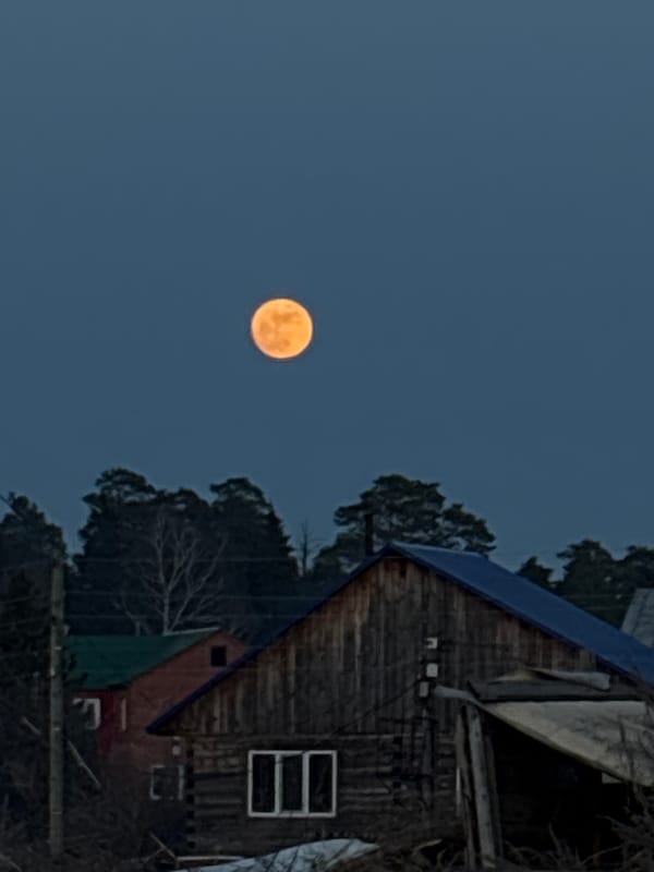 Full moon rises over wooden house in Chaikovsky