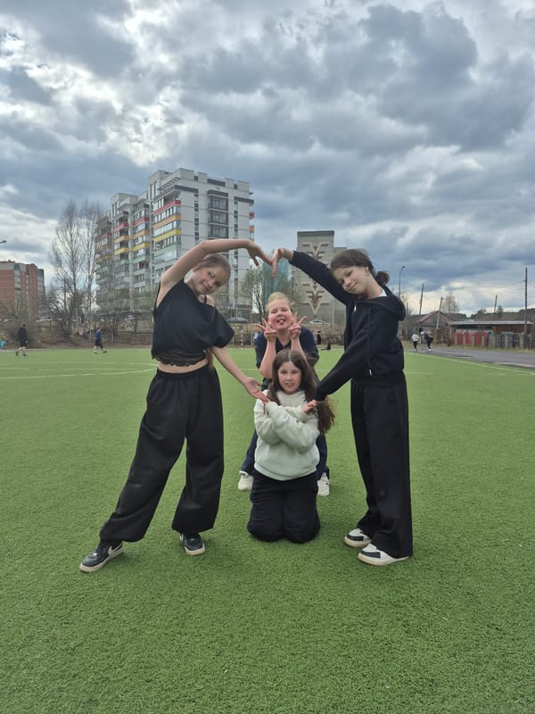 Young women pose playfully on sports field in Chaikovsky