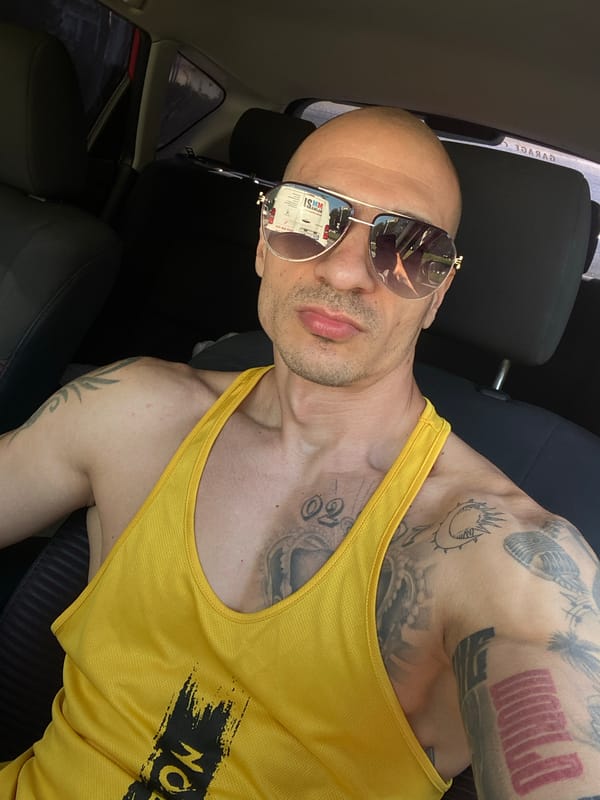 Man in sunglasses, yellow tank top spotted in car