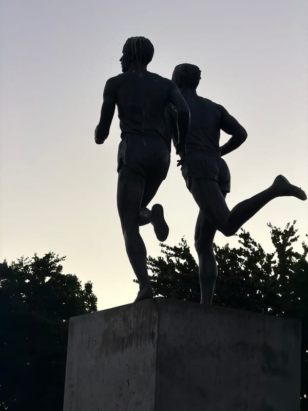Bronze runner statues caught at dusk near a Vancouver trail