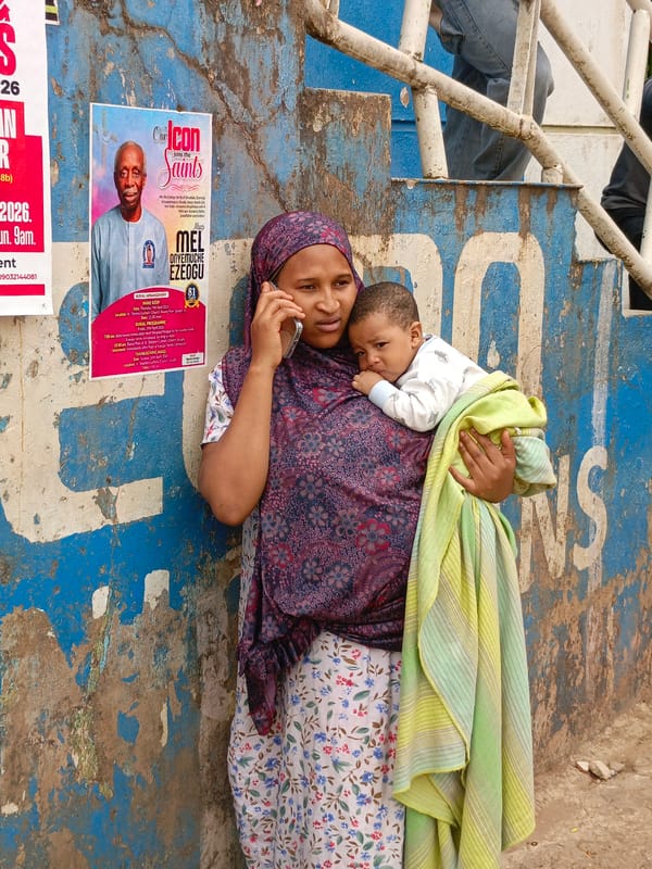 Woman with baby makes phone call against blue wall
