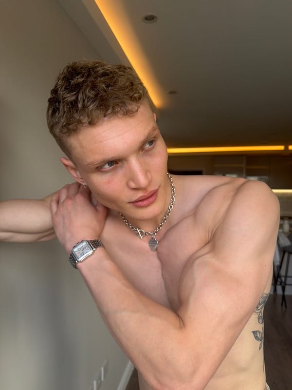 Young man sits on blue structure beside London sidewalk