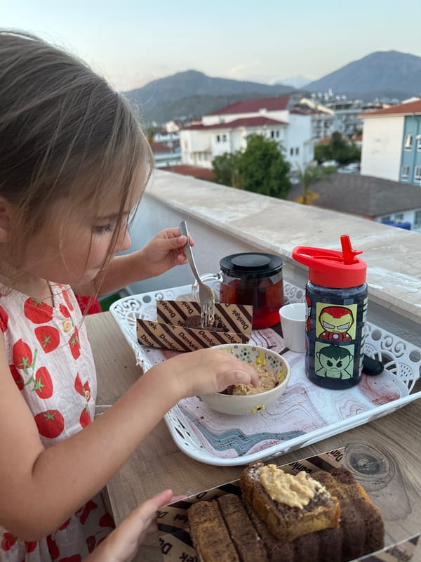 Child dines on terrace as mug held against mountain view