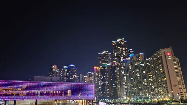 Nighttime scenes captured across Busan include lights, pedestrians, beach performance