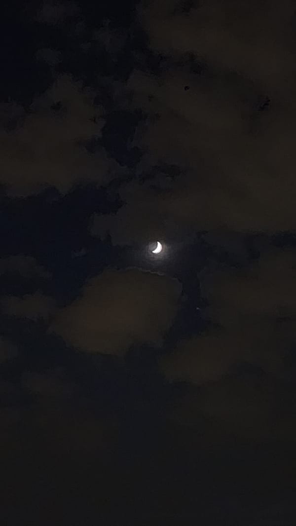 Crescent moon observed through clouds over Moscow evening sky