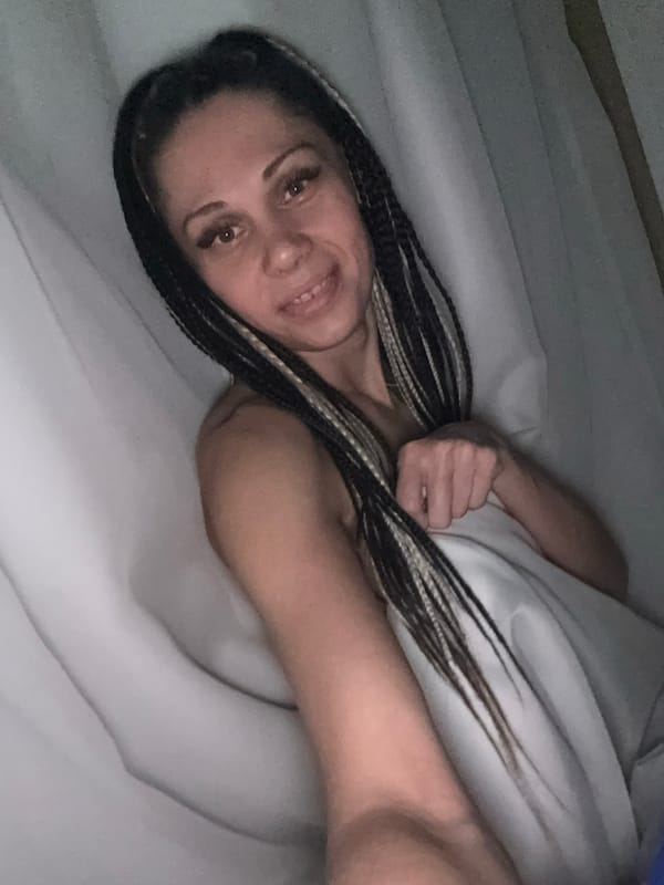 Woman with braided hair holds orange fruit while lying down